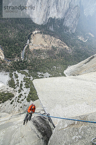 Ein Kletterer klettert hoch oben am El Capitan an einem Seil hinauf