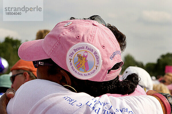 Eine Wanderin und Überlebende wird von einer Freundin umarmt  nachdem sie in Detroit den dreitägigen Komen-Spaziergang gegen Brustkrebs absolviert hat.