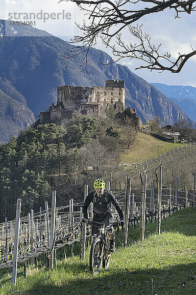 Mountainbiker unterwegs mit Ruinenstruktur im Hintergrund