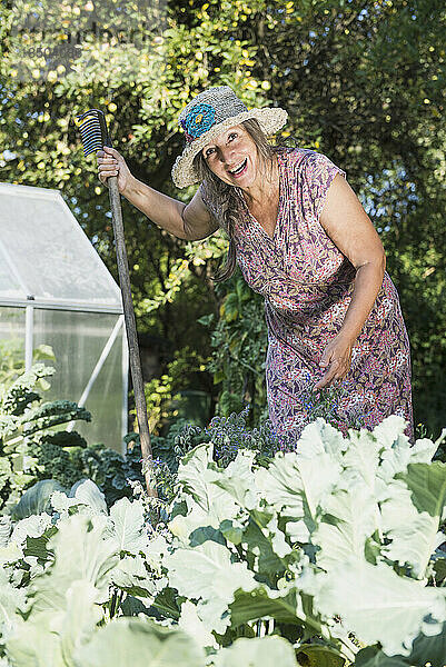 Glückliche Frau mit einem Rechen im Garten  Altötting  Bayern  Deutschland