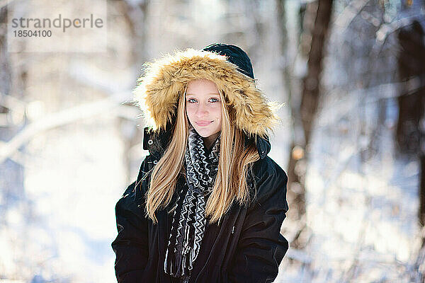 Schönes Teenager-Mädchen in Parka und Schal draußen im Schnee.