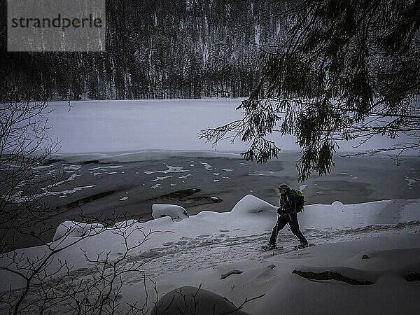 Mann wandert mit Schneeschuhen am Ufer des Feldsees  Schwarzwald  Baden-Württemberg  Deutschland