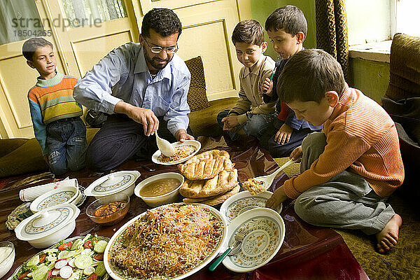 Ein Mann serviert das Abendessen  während die Kinder seines Haushalts zuschauen.