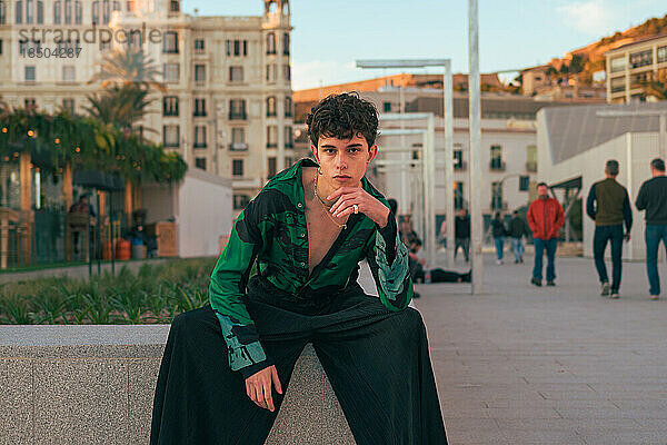 Stilvoller alternativer junger Mann posiert in einer Stadt und blickt in die Kamera
