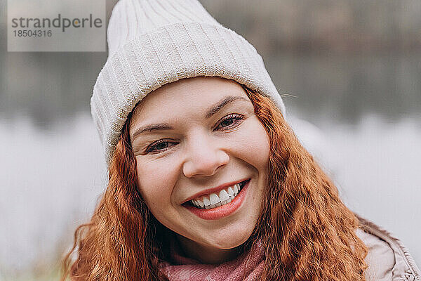 Lockige rothaarige Frau 30-35 mit Hut lächelnd
