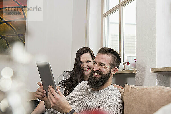 Paar schaut sich digitales Tablet auf Sofa an