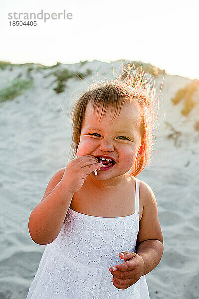 Nahaufnahme eines glücklichen Kleinkindmädchens mit Sauger am Strand in San Diego
