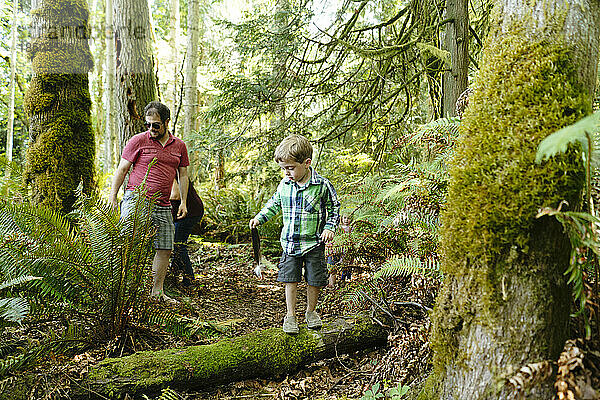 Ein Junge hält eine Weißkopfseeadlerfeder in der Hand  während er mit seiner Familie wandert
