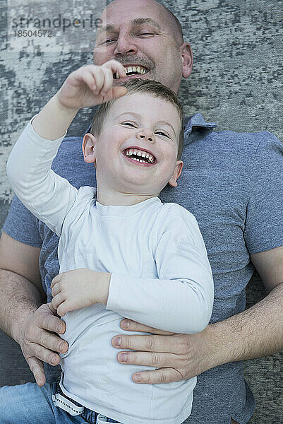 Sohn und Vater haben Spaß daran  auf dem Teppich zu liegen