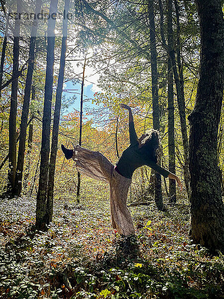 Frau tanzt zwischen Bäumen im Wald