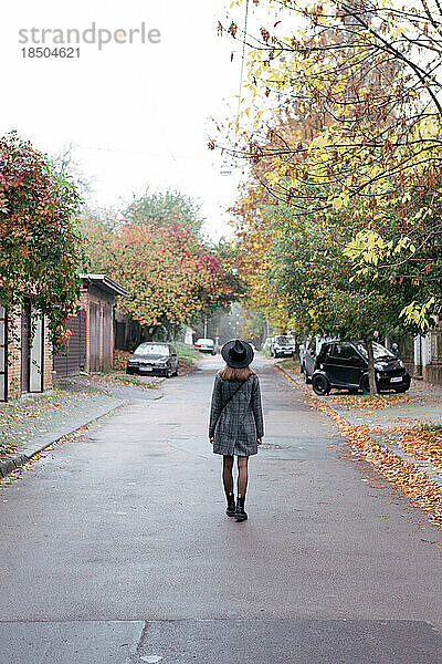 Porträt einer jungen Frau in einem grauen Mantel auf einer herbstlichen Stadtstraße