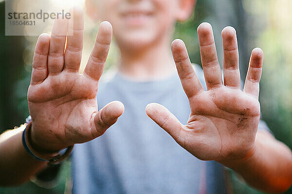 Kinder mit schmutzigen Händen spielen draußen im Wald im Naturabenteuer