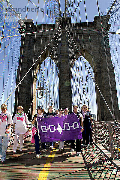 Teammitglieder von „Mohawk Spirit“ tragen während des Avon Walk for Breast Cancer in New York eine Mohawk-Flagge über die Brooklyn Bridge