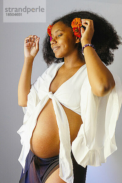 Eine selbstbewusste  schöne schwangere Frau steht mit erhobenen Armen da