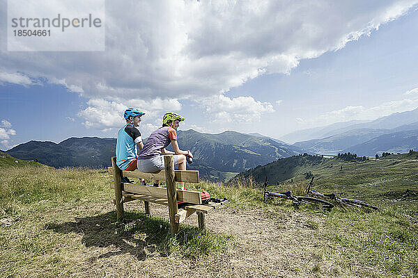 Junges Mountainbiker-Paar sitzt auf einer Bank in alpiner Landschaft  Zillertal  Tirol  Österreich