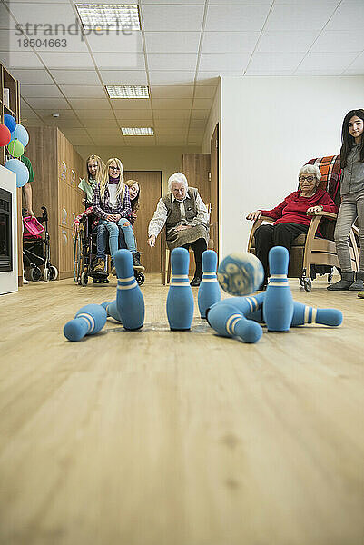 Mädchen spielen Bowling mit älteren Frauen im Seniorenheim