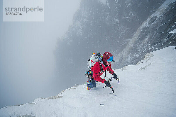 Eiskletterer klettert im Winter auf eine steile Eiswand