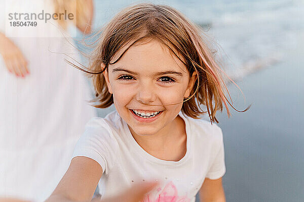 Glückliches kleines Mädchen mit Quads lacht fröhlich am Strand