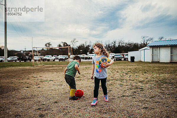 Junge und Mädchen spielen draußen zusammen Fußball