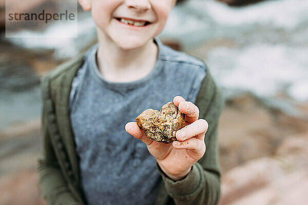 Nahaufnahme eines herzförmigen Felsens in der Hand des Kindes
