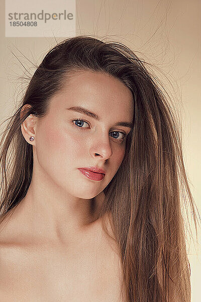 Schönheitsgesicht einer jungen Frau mit natürlichem Make-up auf Beige