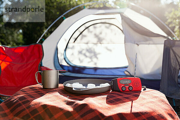 Leerer Campingplatz mit Zelt und Campingstuhl an einem sonnigen Tag im Freien.
