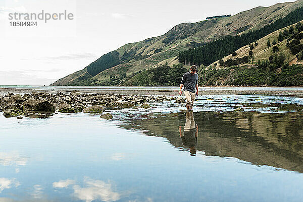Mann läuft bei Ebbe in Neuseeland im Wasser