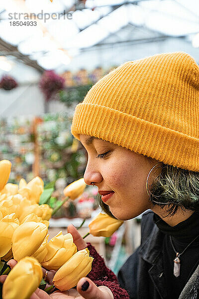 Junge Frau berührt gelbe Tulpen im Floristen. Blumen kaufen.