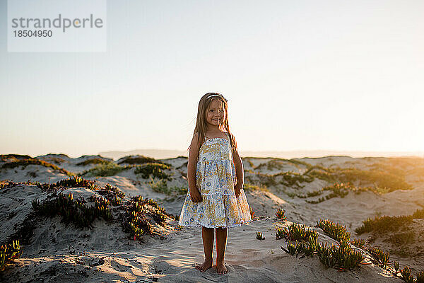Vierjähriges Mädchen posiert auf Sanddünen am Coronado Beach in San Diego