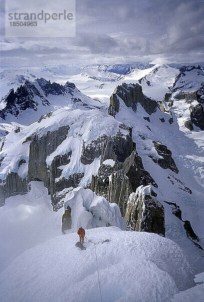 Ein Bergsteiger überquert den Westgrat des Cerro Torre im Schneegestöber  im Hintergrund Cerros Piergiorgio und Marconi  Argentinien