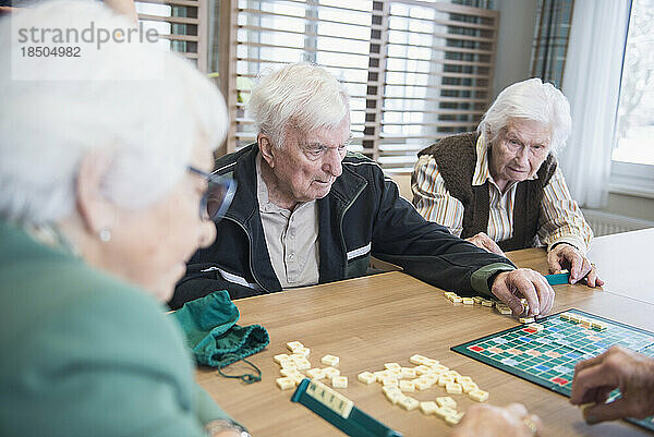 Senior inhabitants playing board game in rest home