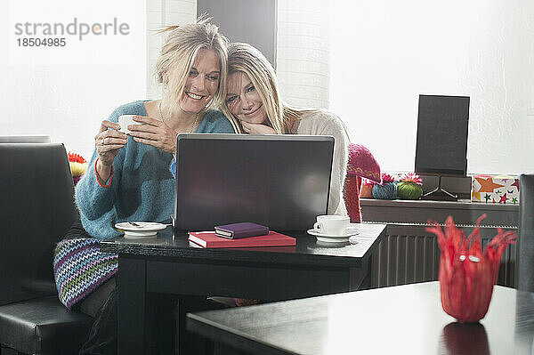 Zwei Freunde benutzen Laptop und trinken Kaffee im Café  Bayern  Deutschland