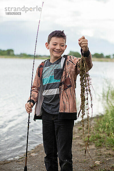 Junge lacht über beim Angeln gefangene Algen