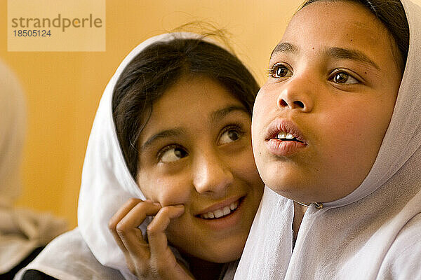 Girls in white head scarves attend an accelerated school program in Kabul.