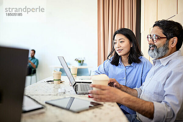 Geschäftsfrau teilt Laptop mit Kollegin  die im Café sitzt