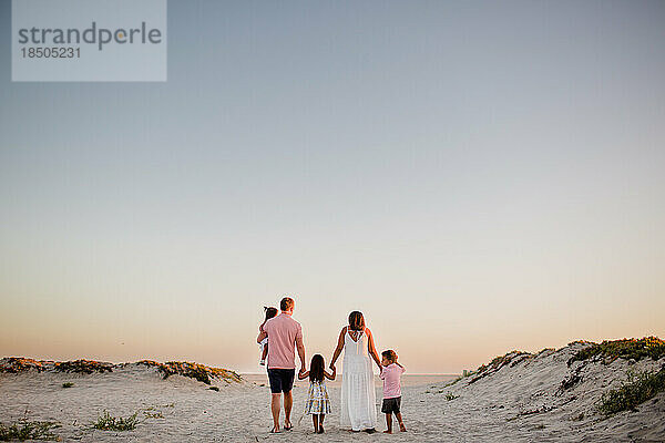 Fünfköpfige Familie hält Händchen und geht am Coronado Beach in San Diego spazieren