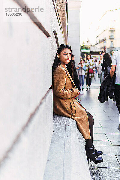 Asiatisches Mädchen sitzt auf der Straße und wartet auf ihre Freunde