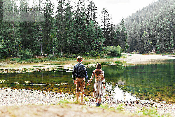 Mann und Frau halten Händchen in der Nähe eines Waldsees