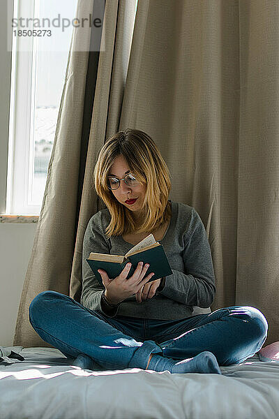 Junge Frau liest ein Buch in ihrem Zimmer