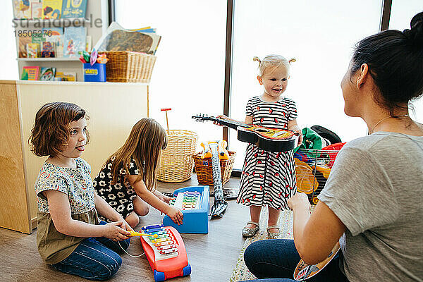 Kleinkindmädchen  das eine Gitarre hält  interagiert mit Lehrer