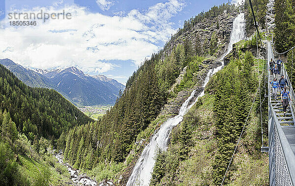 Gruppe von Kletterern  die durch eine Hängetreppe am malerischen Stuibenfall-Wasserfall  Ötztal  Tirol  Österreich  wandern