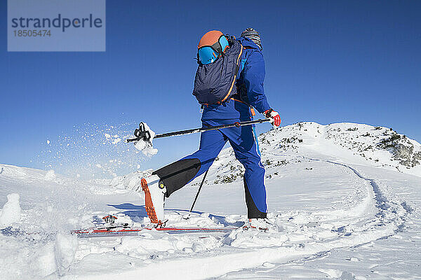 Rückansicht eines Skifahrers  der auf Schnee gegen den Himmel läuft