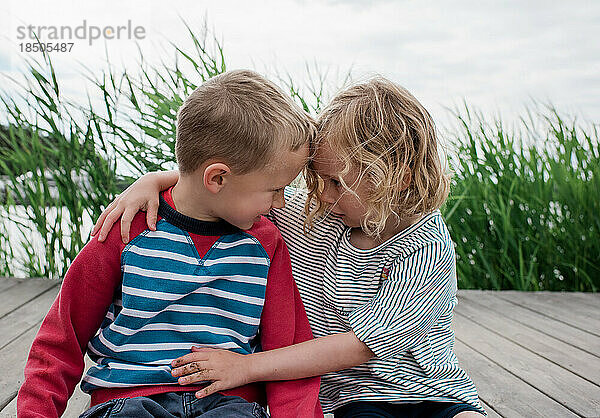 Bruder und Schwester schauen sich im Urlaub am Strand an