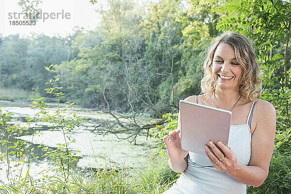 Schöne Frau mit digitalem Tablet am See  Bayern  Deutschland