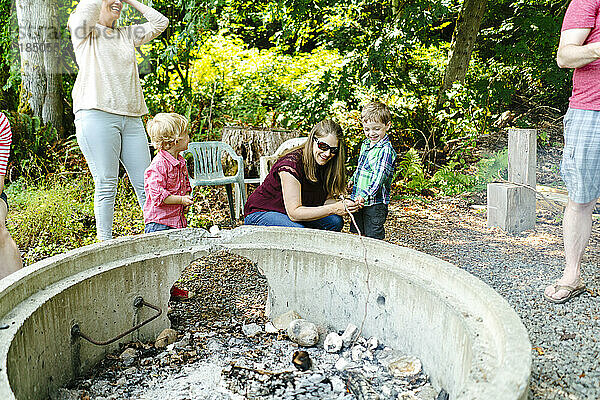 Familie und Freunde versammeln sich am Lagerfeuer  um Marshmallows zu rösten