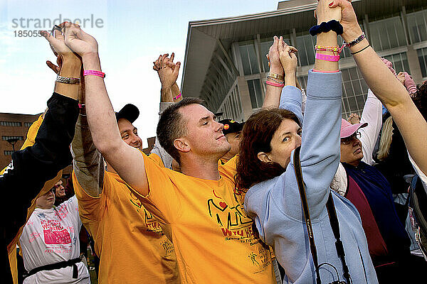 Paul Boulanger raises his hands with others at the start of the Avon Walk for Breast Cancer in Boston.