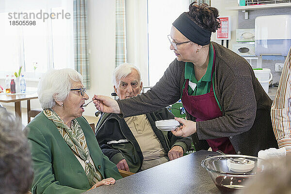 Krankenschwester gibt Seniorin im Pflegeheim Essen nach Geschmack