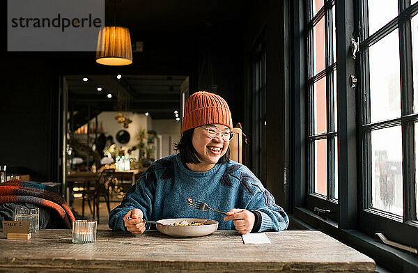 Asiatische Frau isst glücklich in einem Café zu Mittag