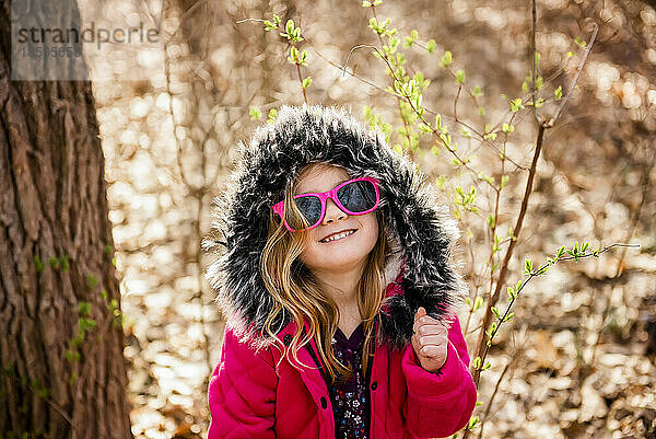 Lächelndes Mädchen trägt Sonnenbrille und tanzt im Herbst im Wald