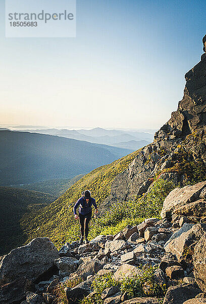 Frau wandert bei Sonnenaufgang auf Felsen am Berg